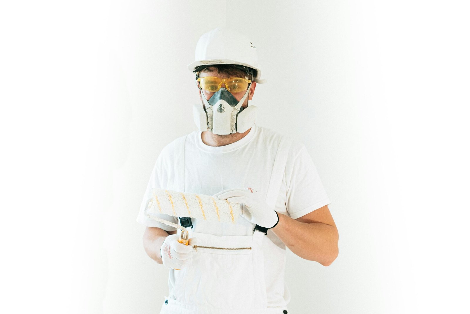 A professional painter wearing safety gear holding a paint roller, ready for work.
